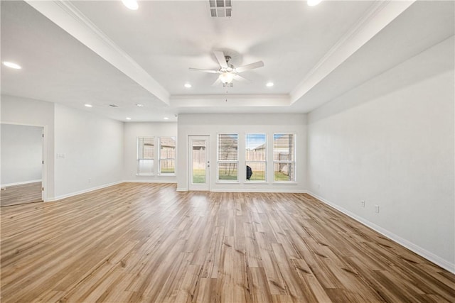 unfurnished living room with plenty of natural light, a raised ceiling, and light wood-type flooring