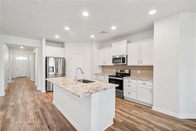 kitchen featuring a kitchen island with sink, white cabinets, sink, light wood-type flooring, and stainless steel appliances