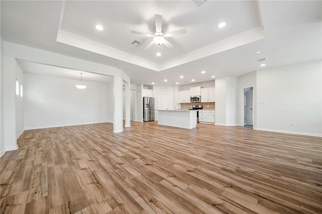 unfurnished living room with a tray ceiling, ornamental molding, and light wood-type flooring