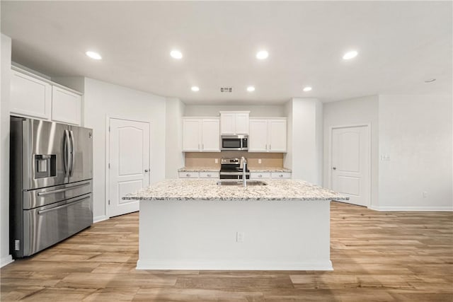 kitchen with a kitchen island with sink, white cabinets, sink, light wood-type flooring, and appliances with stainless steel finishes