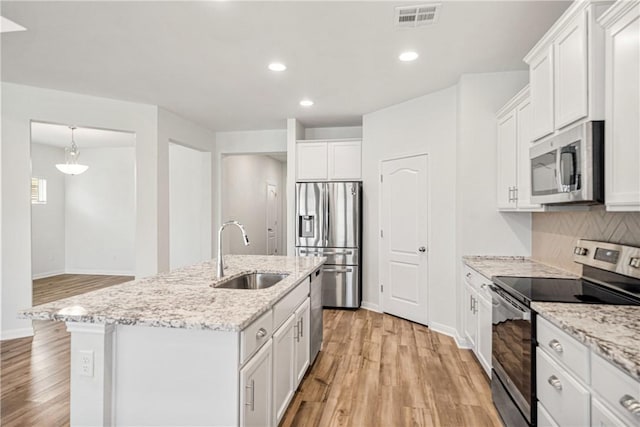 kitchen with sink, stainless steel appliances, a center island with sink, white cabinets, and light wood-type flooring