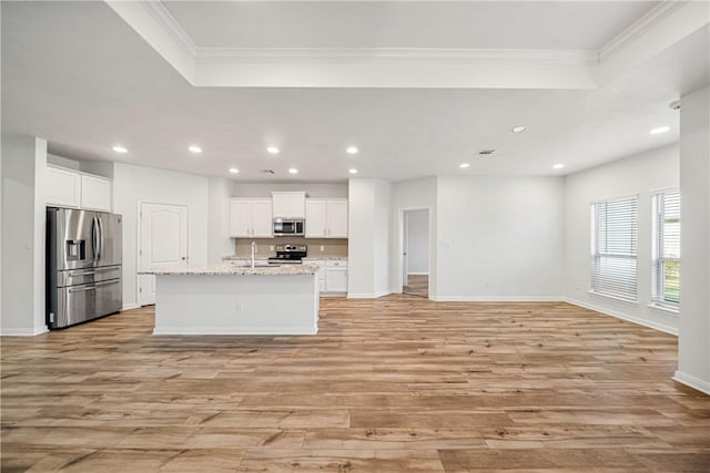 kitchen featuring a center island with sink, white cabinets, light hardwood / wood-style flooring, light stone counters, and stainless steel appliances