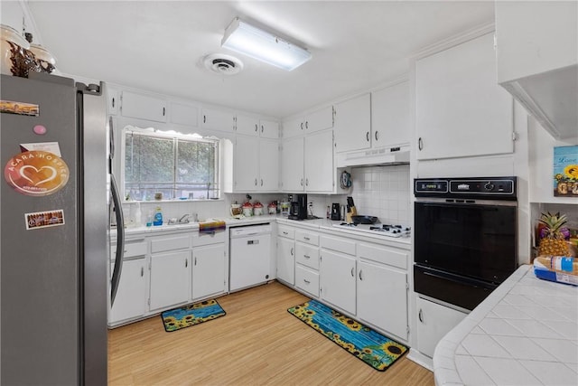 kitchen with light wood-type flooring, a warming drawer, under cabinet range hood, white appliances, and white cabinetry