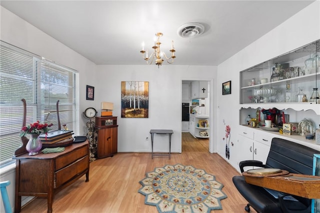 dining area with light wood-style floors, an inviting chandelier, and visible vents