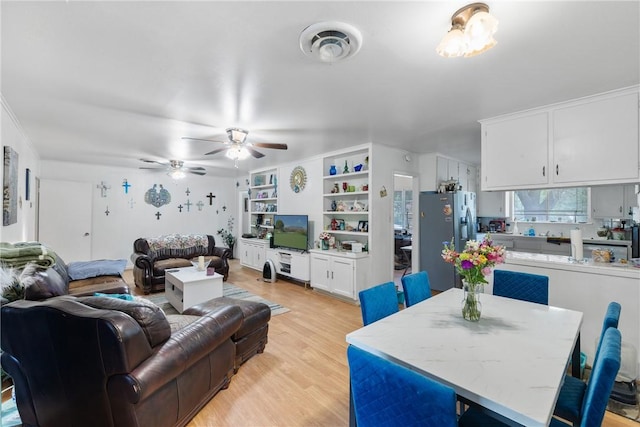 living area with visible vents, light wood-style floors, and ceiling fan