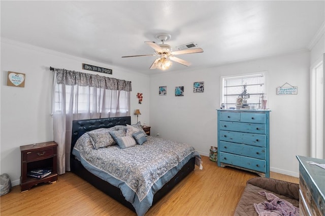 bedroom with crown molding, light wood finished floors, a ceiling fan, baseboards, and visible vents