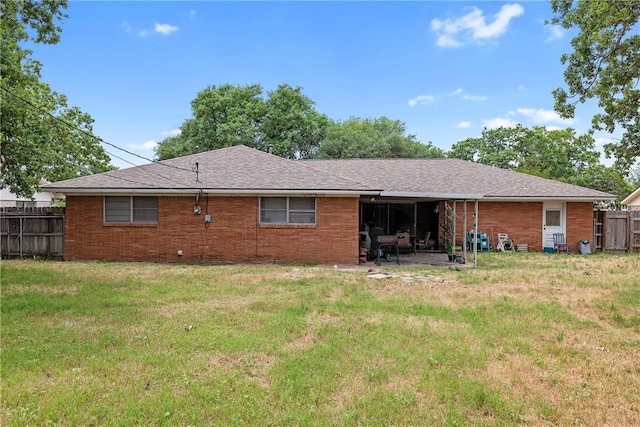 rear view of property with fence, a patio, a yard, and brick siding