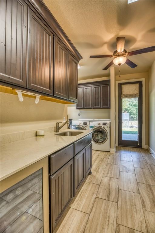 washroom with a textured ceiling, a sink, a ceiling fan, baseboards, and cabinet space