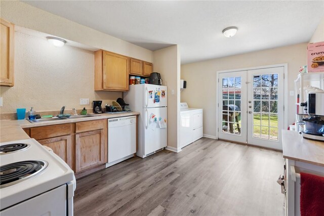 kitchen featuring light wood finished floors, white appliances, washer / dryer, light countertops, and a sink