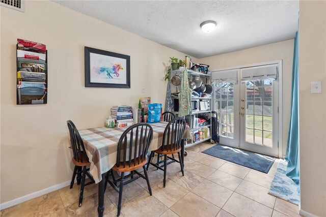 dining space featuring visible vents, baseboards, tile patterned flooring, a textured ceiling, and french doors