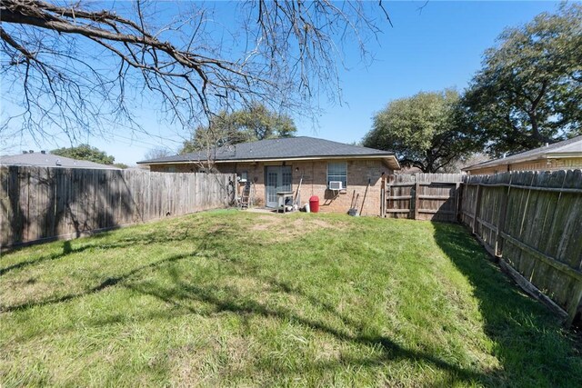 back of property with a fenced backyard, a lawn, and brick siding