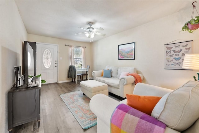 living room featuring baseboards, a ceiling fan, and wood finished floors