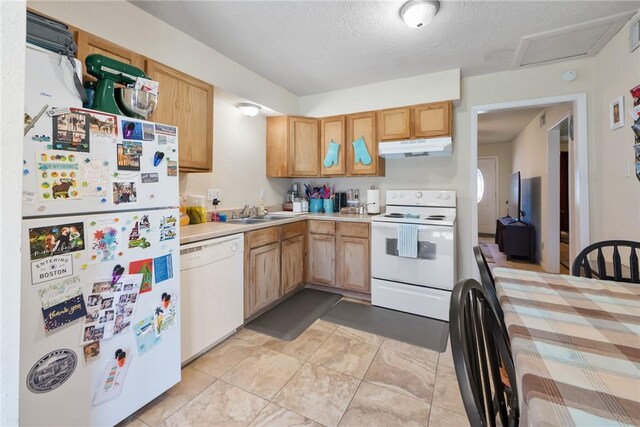 kitchen with white appliances, light countertops, a textured ceiling, under cabinet range hood, and a sink