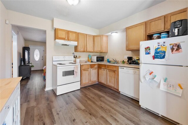 kitchen with white appliances, light countertops, under cabinet range hood, and wood finished floors