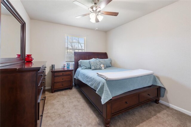 bedroom with a ceiling fan, light colored carpet, and baseboards