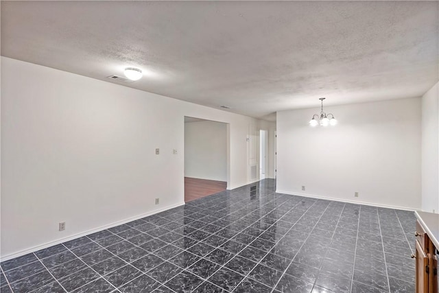 unfurnished room featuring a chandelier and a textured ceiling