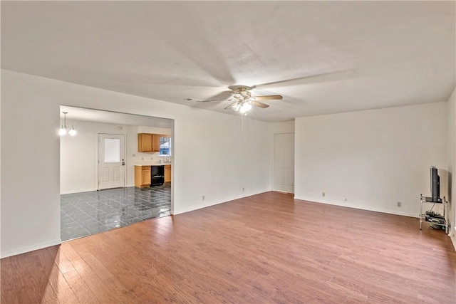 unfurnished living room with dark wood-type flooring and ceiling fan with notable chandelier