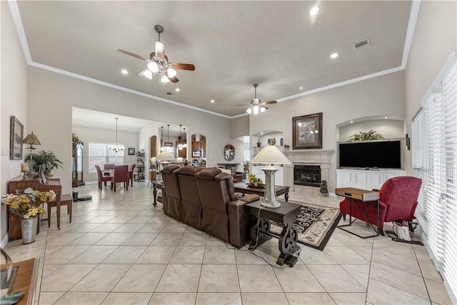 tiled living room with ornamental molding, ceiling fan with notable chandelier, and a fireplace