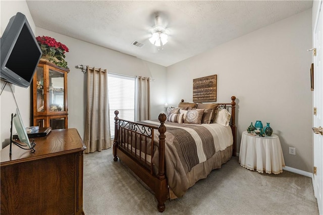 carpeted bedroom with ceiling fan and a textured ceiling