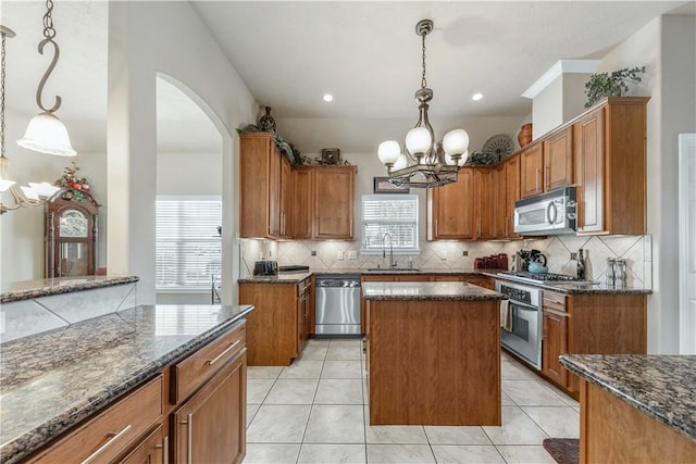 kitchen with pendant lighting, stainless steel appliances, sink, and a kitchen island