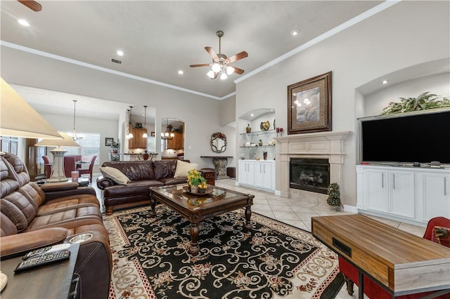 living room with light tile patterned floors, crown molding, a fireplace, built in shelves, and ceiling fan with notable chandelier