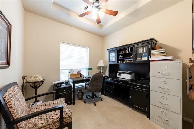 carpeted office space featuring ceiling fan and a raised ceiling