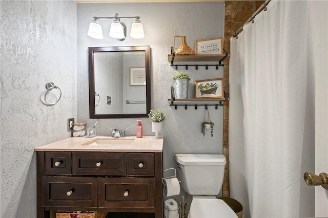 bathroom with vanity, a textured wall, and toilet