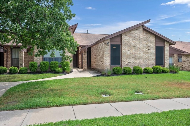 view of front of house featuring brick siding and a front lawn