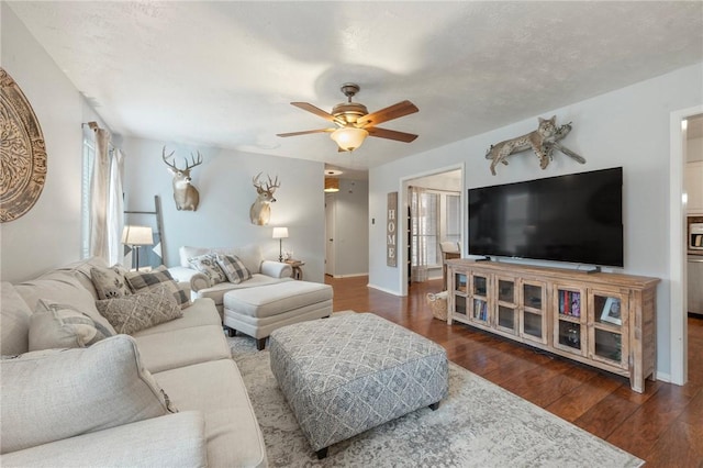 living area featuring baseboards, ceiling fan, and wood finished floors