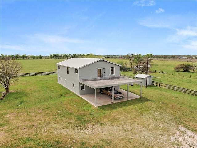 rear view of property with a rural view, fence, and a lawn