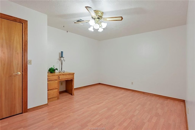 unfurnished room featuring a textured ceiling, baseboards, visible vents, and light wood-style floors