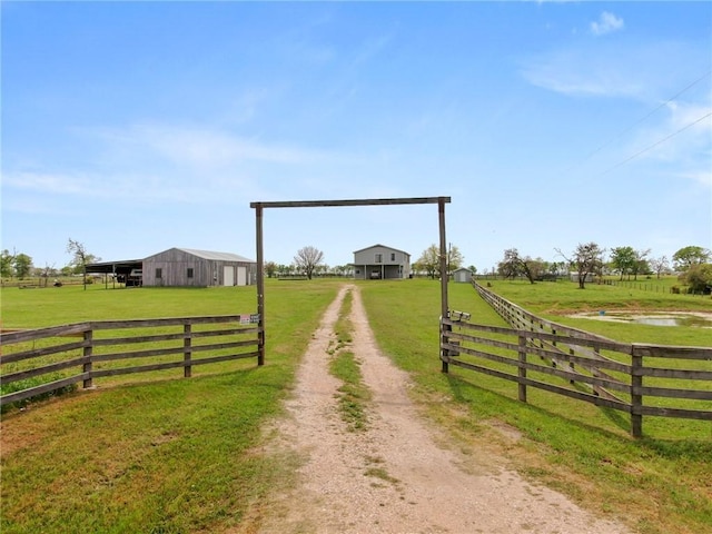 exterior space with driveway, a gated entry, and a rural view