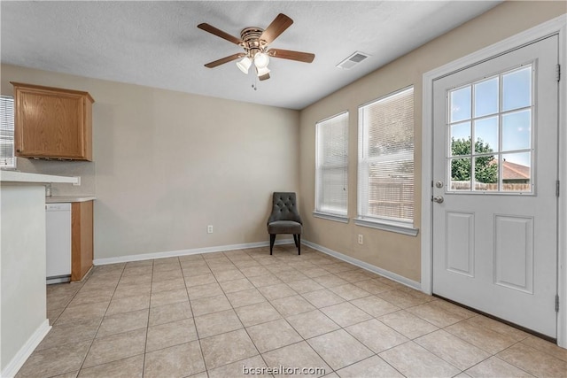 interior space featuring light tile patterned floors, a textured ceiling, and ceiling fan