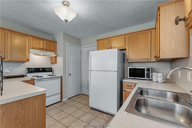 kitchen with a textured ceiling, sink, light tile patterned flooring, and white appliances