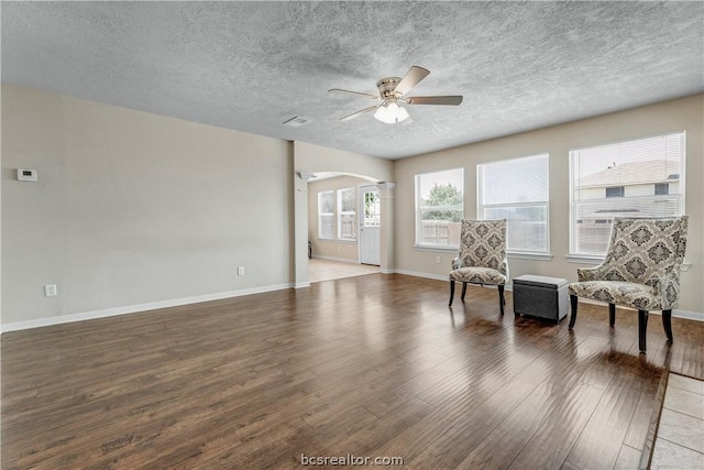 sitting room with ceiling fan, dark hardwood / wood-style flooring, and a textured ceiling