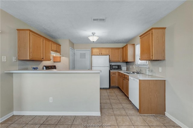 kitchen with a textured ceiling, sink, light tile patterned floors, and white appliances