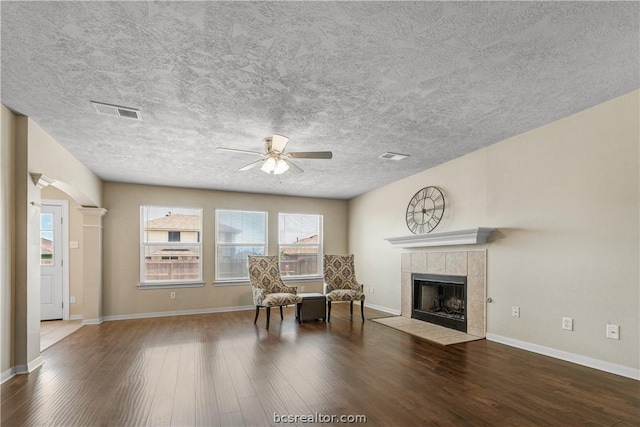 sitting room featuring hardwood / wood-style floors, ceiling fan, a textured ceiling, and a tile fireplace