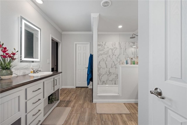 full bath with baseboards, tiled shower, wood finished floors, crown molding, and vanity