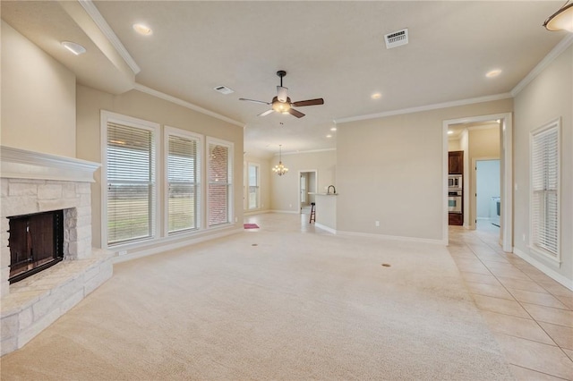 unfurnished living room with light carpet, ceiling fan with notable chandelier, a stone fireplace, and ornamental molding