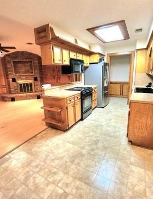 1706 Shawnee St, Navasota, TX 77868 - kitchen featuring black appliances, light countertops, ceiling fan, a wainscoted wall, and open shelves