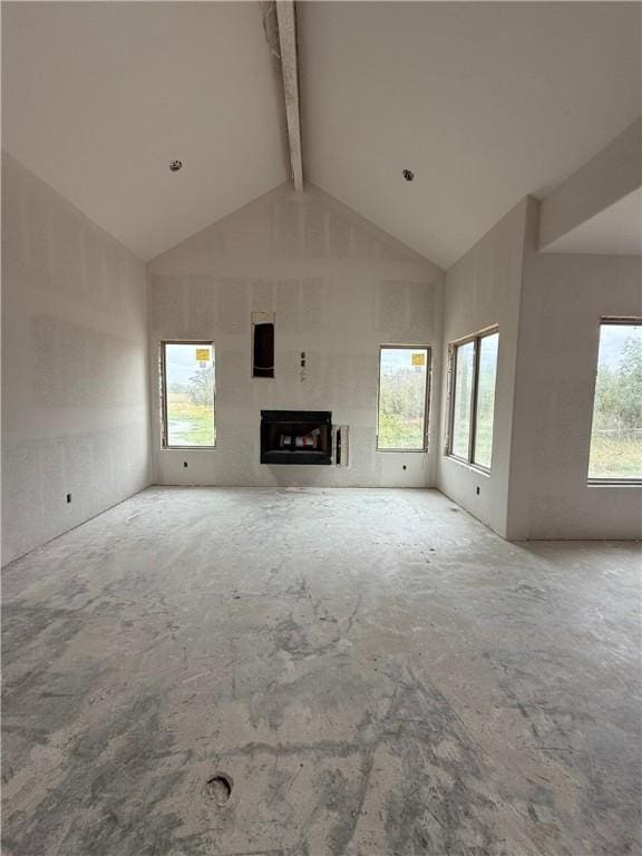 unfurnished living room featuring high vaulted ceiling, beam ceiling, and a wealth of natural light