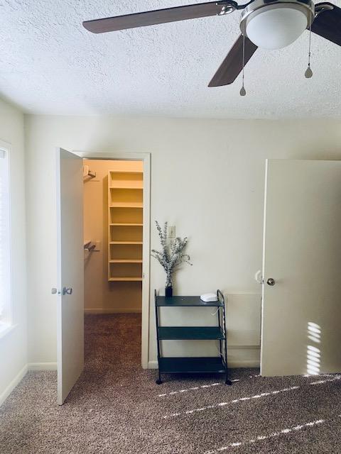 corridor with carpet, baseboards, and a textured ceiling