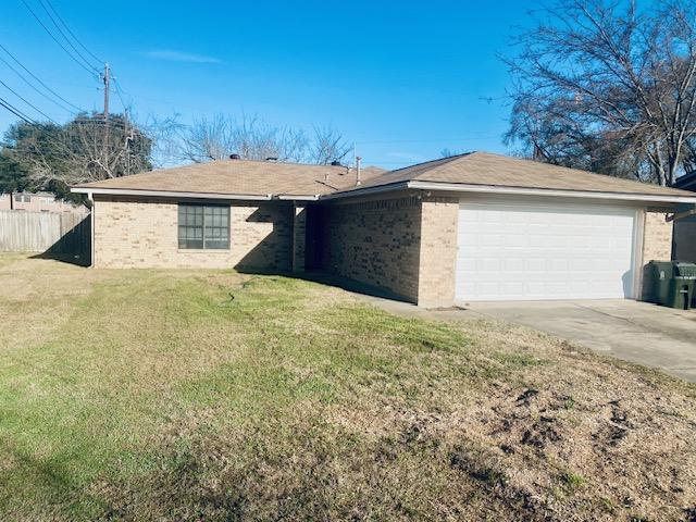 view of front of home with brick siding, concrete driveway, an attached garage, fence, and a front lawn