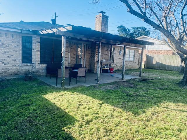 rear view of property featuring a yard, brick siding, a patio, and fence