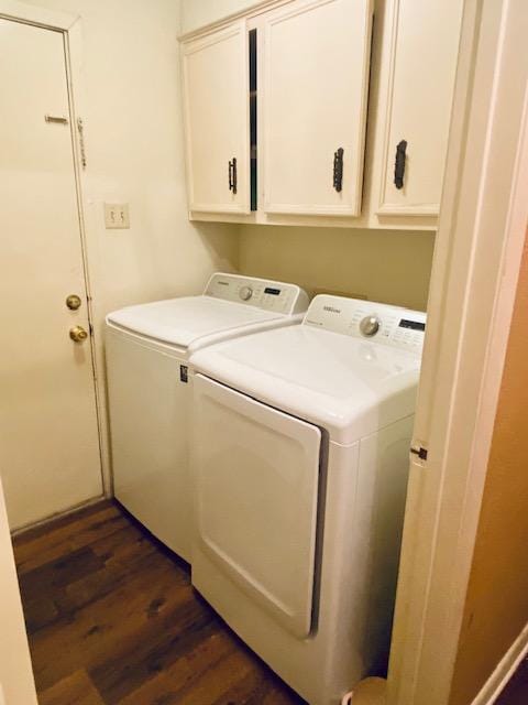 clothes washing area with dark wood finished floors, cabinet space, and washer and dryer