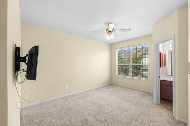 unfurnished bedroom with light carpet, ensuite bath, baseboards, and a ceiling fan