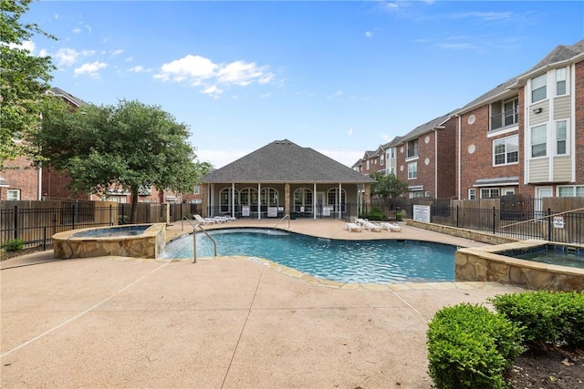 view of pool with fence, a patio, and a pool with connected hot tub