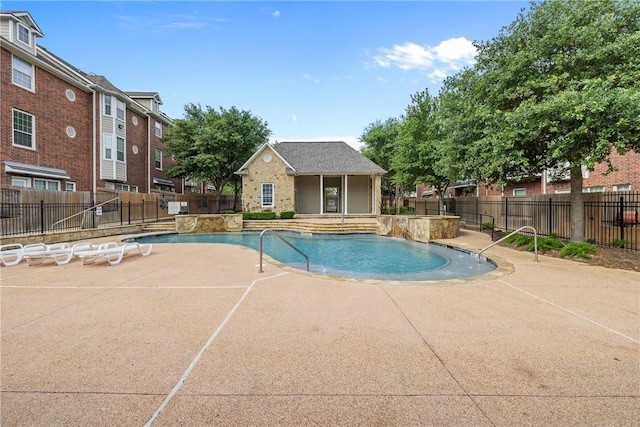 community pool featuring fence, a patio area, and an outbuilding