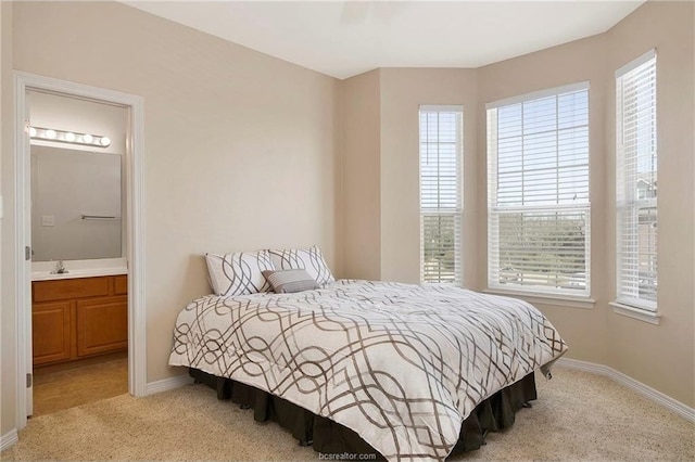 carpeted bedroom with connected bathroom and multiple windows