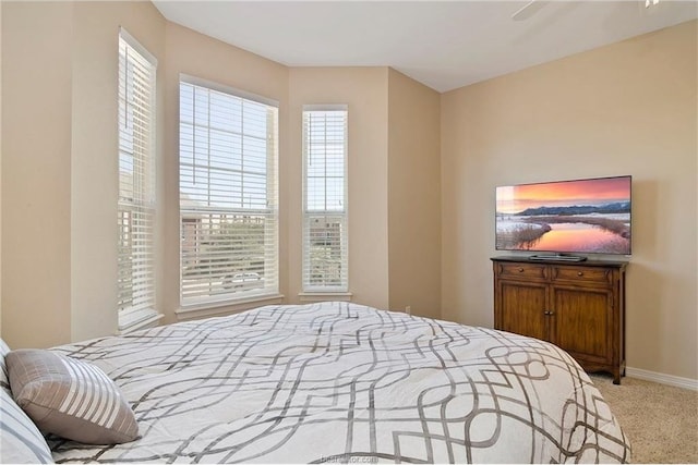 bedroom with multiple windows, light carpet, and ceiling fan